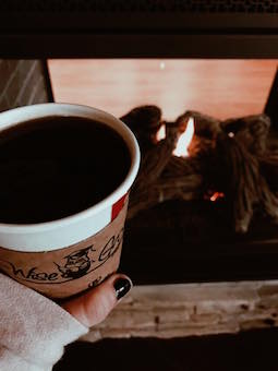Wisegrounds coffee cup in front of fireplace